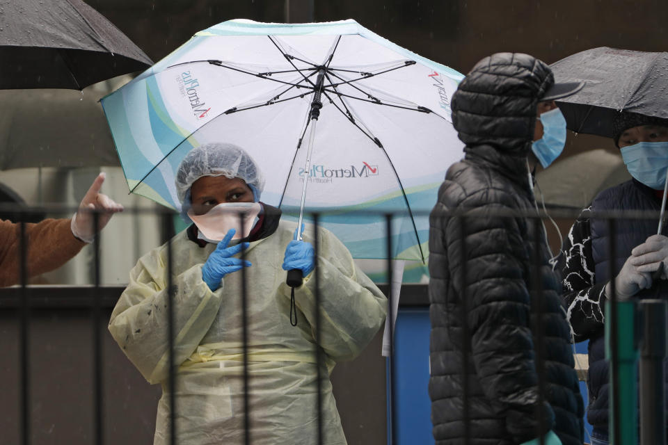 A medical worker points out the COVID-19 testing tent set up outside Elmhurst Hospital Center in New York, Saturday, March 28, 2020. The hospital is caring for a high number of coronavirus patients in the city. The new coronavirus causes mild or moderate symptoms for most people, but for some, especially older adults and people with existing health problems, it can cause more severe illness or death. (AP Photo/Kathy Willens)