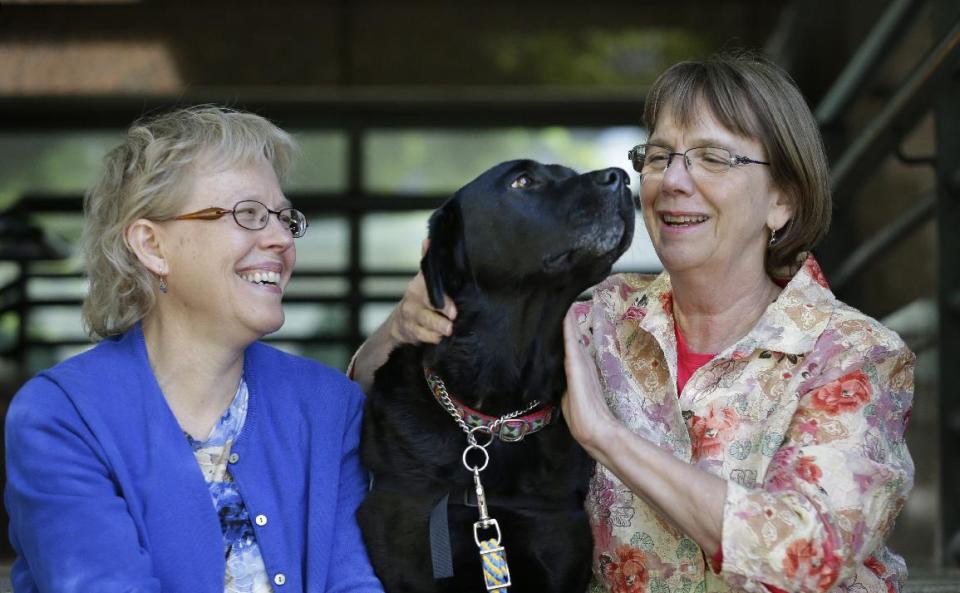 In this photo taken Friday, May 3, 2013, courthouse dog Molly B, center, sits with Celeste Walsen, left, and Ellen O'Neill-Stephens, in Seattle. As canine companions in courthouses, dogs have helped thousands of victims and witnesses, but some challenges are working their way through the courts, driven by attorneys who claim the dogs are distractions or sympathy magnets. So far, all lower courts have upheld the use of dogs. (AP Photo/Elaine Thompson)