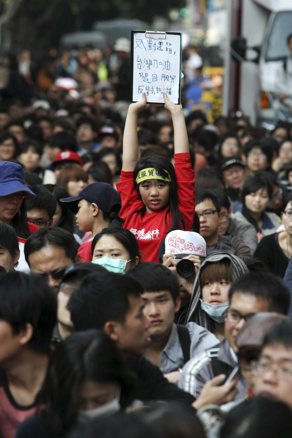 A woman holds a banner which reads "Anti Black Box. Turn Back Trade Pact. Taiwan Go Go Go." in support of Taiwan as the demonstrators surround the legislature in Taipei, Taiwan, Sunday, March 23, 2014. Opponents of a trade pact with China have demonstrated in and around Taiwan's legislature since Tuesday, in the most serious challenge to date to President Ma Ying-jeou's policy of moving the democratic island of 23 million people economically closer to Communist China. (AP Photo/Chiang Ying-ying)