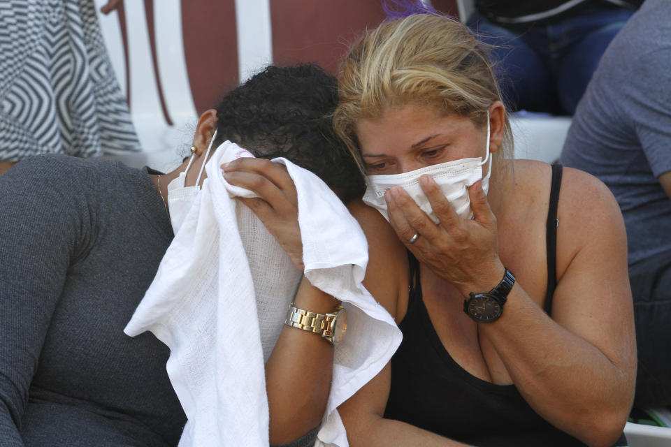 A woman wait outside the coroner's office in Altamira, Brazil, Tuesday, July 30, 2019. Relatives of inmates killed during a prison riot in northern Brazil gathered at the coroner's office Tuesday to identify the 57 victims, with some passing out at seeing the beheaded corpse of a loved one. (AP Photo/Raimundo Pacco)