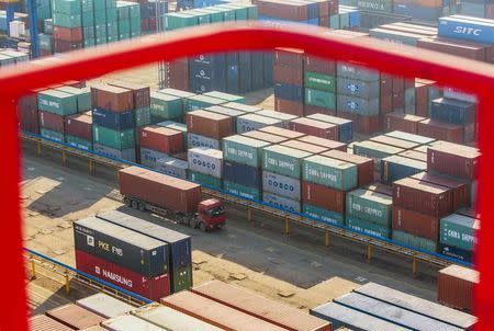 A truck drives past shipping containers at a port in Lianyungang, Jiangsu province January 23, 2015. REUTERS/China Daily