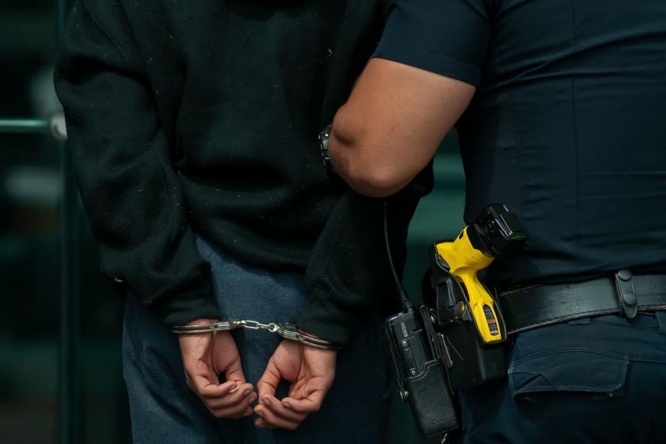 NYPD officers walk a juvenile defendant through the front door of the Bronx Hall of Justice on East 161st Street for an arraignment, Aug. 13, 2019. (Ben Fractenberg / THE CITY)