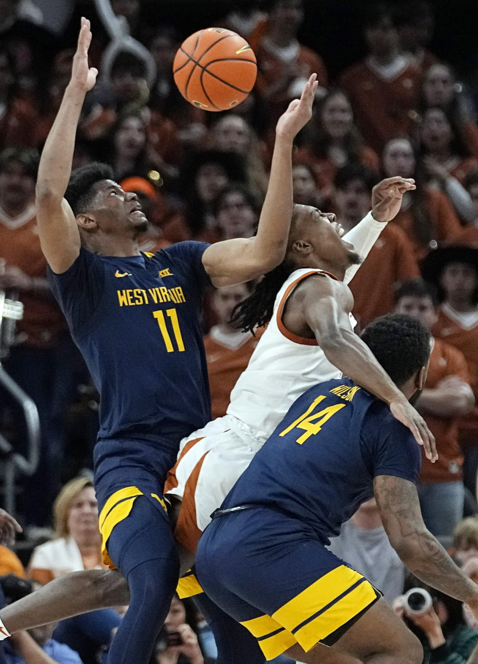 Texas guard Marcus Carr, center, loses control of the ball as he is defended by West Virginia forward Mohamed Wague (11) and guard Seth Wilson (14) during the first half of an NCAA college basketball game in Austin, Texas, Saturday, Feb. 11, 2023. (AP Photo/Eric Gay)