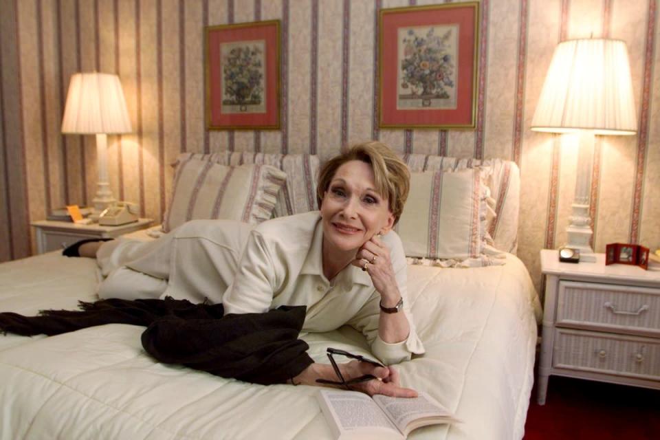<p>Grandmillennial style was big in the '90s, too—except most millennials were still children at the time! Actress Siân Phillips is pictured here in an unnamed New York hotel marked by floral wallpaper and frilly pillows with matching shams, plus white wicker end tables.</p>