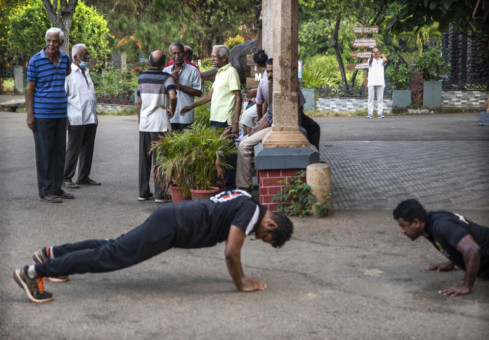 Elderly men chat as two youth perform push ups in the morning in Thiruvanathapuram, Kerala state, India, March 17, 2023. In this coastal state in India's southern tip, the aging population provides a stark contrast to the young India of the north. The most literate state in India, Kerala is also the fastest aging part of the country. Declining fertility and increasing longevity have been contributing to the demographic shifts in the State. (AP Photo/ R S Iyer)