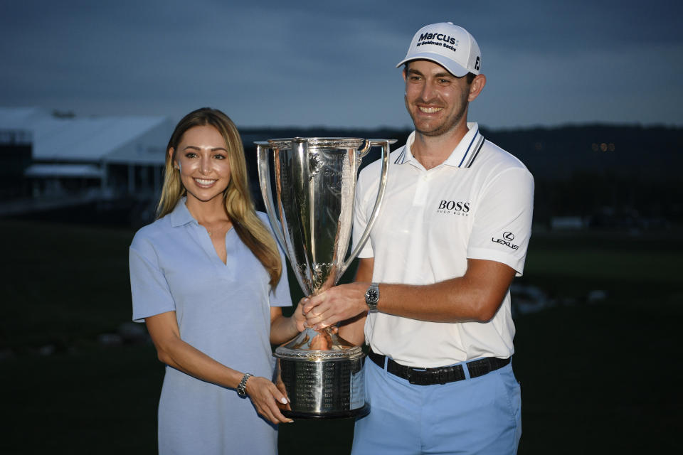 Patrick Cantlay, right, poses with his girlfriend, Nikki Guidish and the FedEx Cup after he won the BMW Championship golf tournament, Sunday, Aug. 29, 2021, at Caves Valley Golf Club in Owings Mills, Md. (AP Photo/Nick Wass)