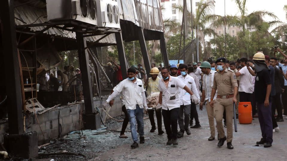 Rescuers carry the body of a person killed in the fire at the gaming arcade in Rajkot, India, on May 25. - Chirag Chotaliya/AP