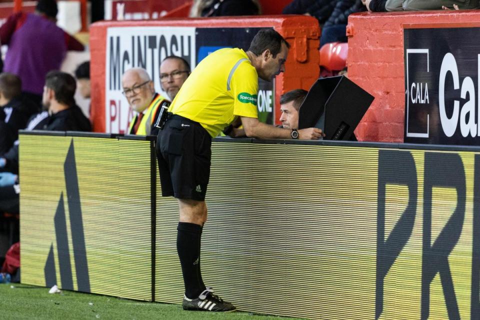 Referee Alan Muir checks a pitchside monitor at Pittodrie <i>(Image: SNS)</i>