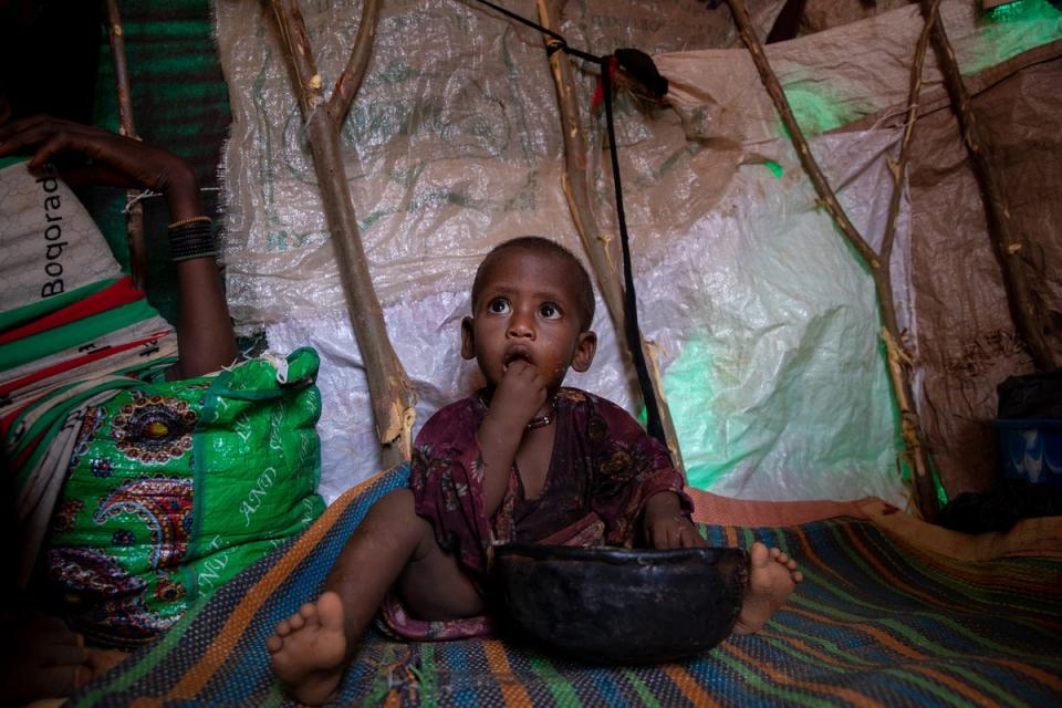 Fatun plays with a bag of WFP supplied super cereal inside the small shelter (WFP/Samantha Reinders)