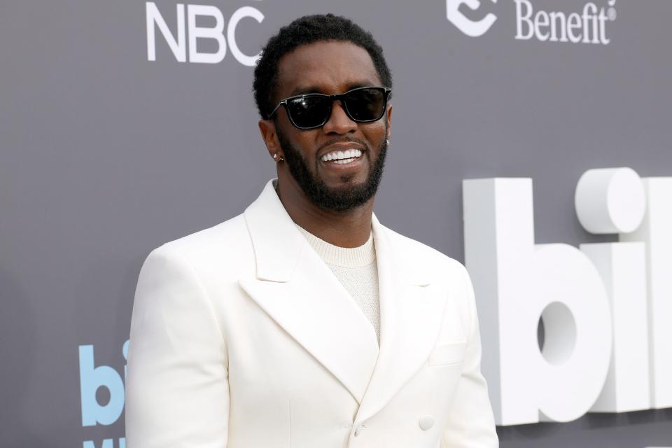 Sean Combs in a white suit and black sunglasses