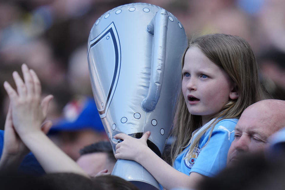 A young supporter holds mock trophy during the English Premier League soccer match between Manchester City and Chelsea at the Etihad Stadium in Manchester, England, Sunday, May 21, 2023. (AP Photo/Jon Super)