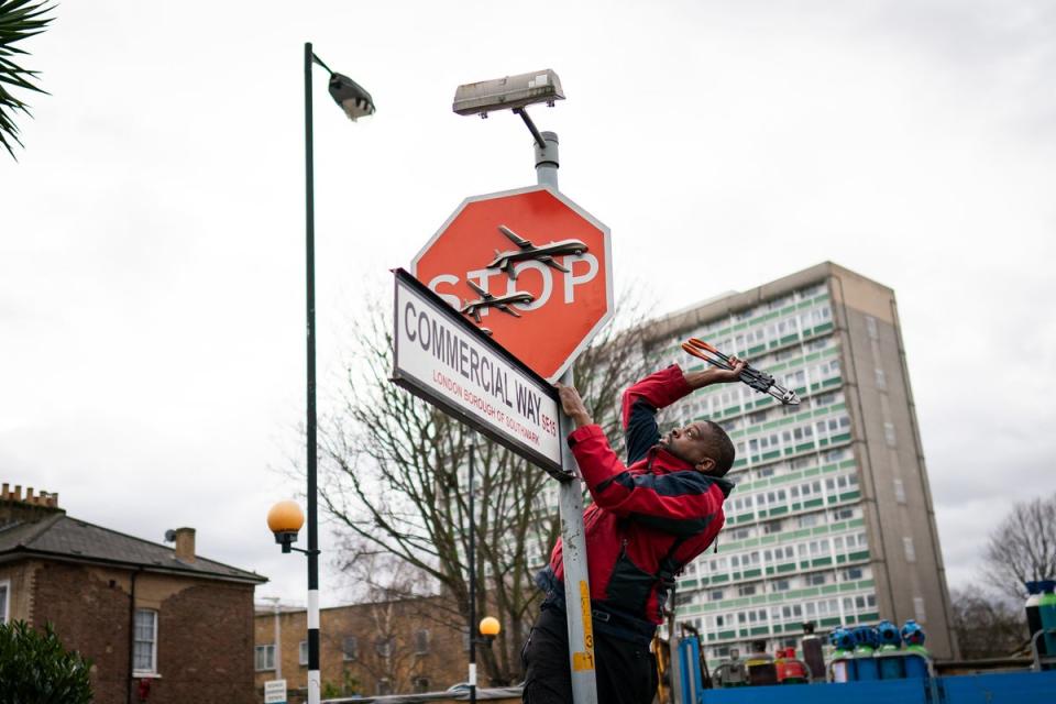 A man removes a piece of art by Banksy at the intersection of Southampton Way and Commercial Way in Peckham (Aaron Chown/PA)