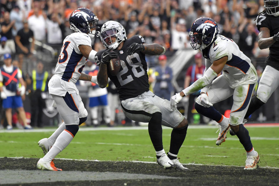 Las Vegas Raiders running back Josh Jacobs (28) scores a touchdown as Denver Broncos cornerback Ronald Darby (23) defends during the second half of an NFL football game, Sunday, Oct. 2, 2022, in Las Vegas. (AP Photo/David Becker)