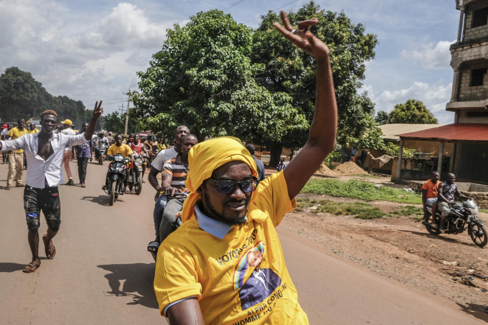 Supporters of the ruling Rally of the Guinean People (RPG) party, one wearing a t-shirt of the president, ride on motorbikes at a demonstration against the opposition Union of Democratic Forces of Guinea (UFDG) party and to block the visit of their leader, in the streets of Kankan, Guinea Sunday, Oct. 11, 2020. The stage is set for Oct. 18 presidential elections pitting incumbent President Alpha Conde, 82, who is bidding for a third term, against opposition leader Cellou Dalein Diallo, who was previously defeated by Conde in both the 2010 and 2015 elections. (AP Photo/Sadak Souici)