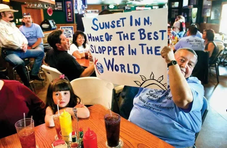 File photo - Glenn Chavez (right) holds up a sign proclaiming the Sunset Inn slopper best in the world during the filming of the Travel Channel's ‘Food Wars’ rally in 2010.
