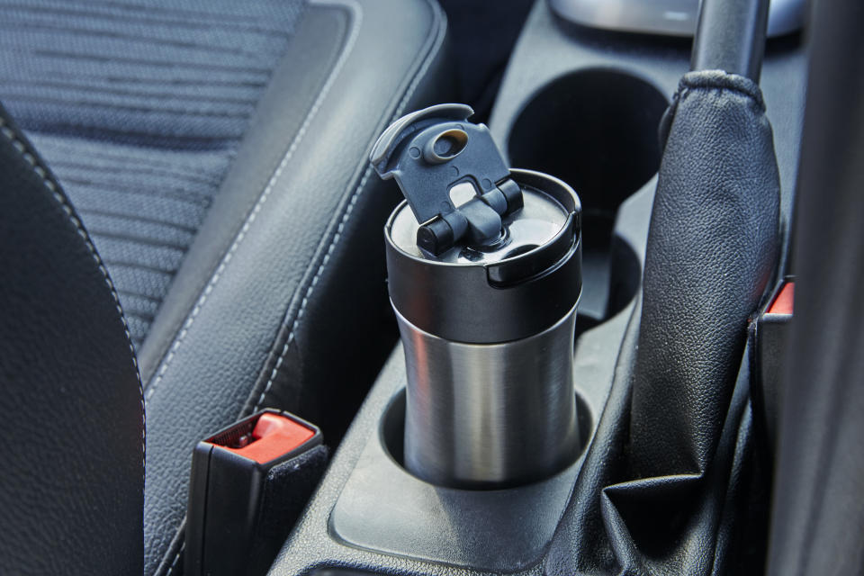 Close up of reusable metal coffee cup o coffee cup holder on the interior of car with gear stick and handbrake