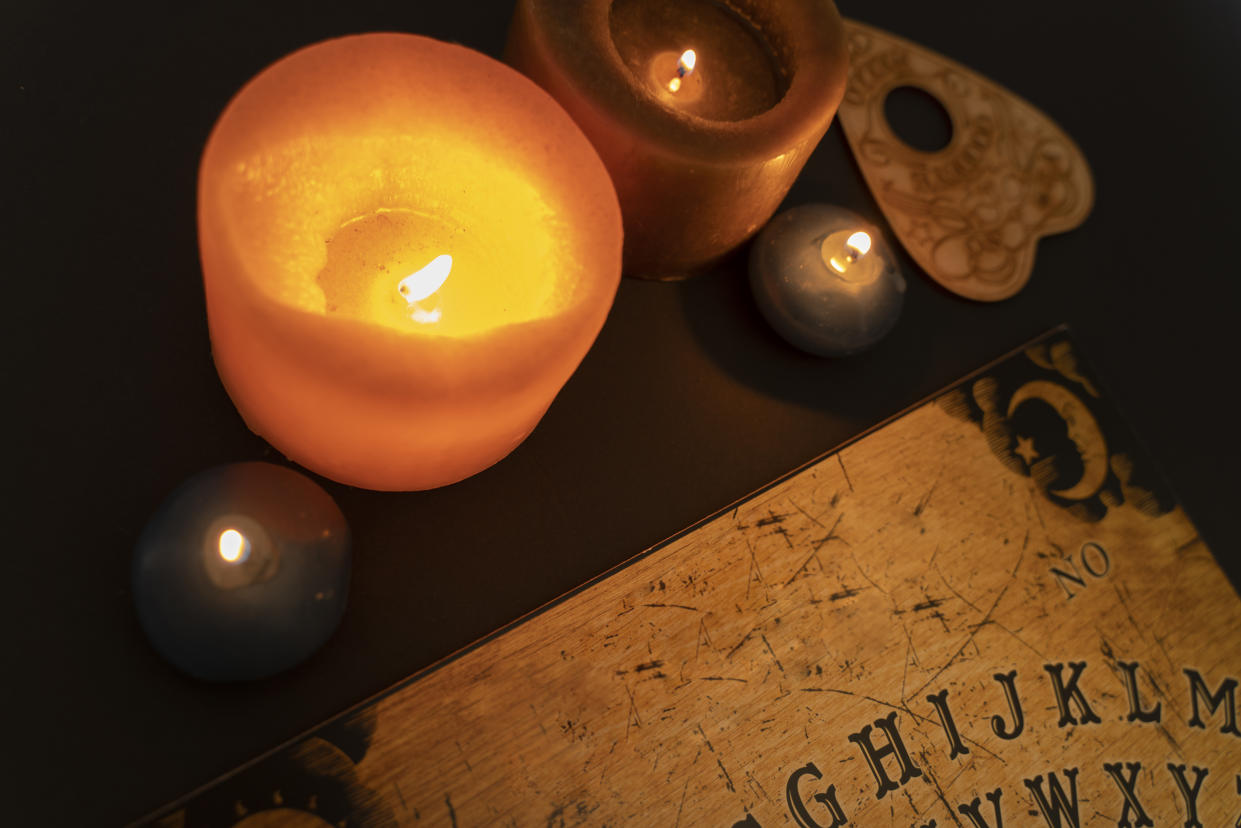 Above view of ouija board on dark background by candlelight