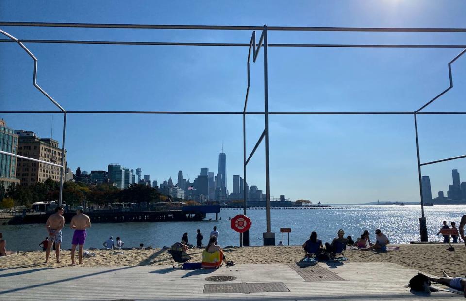 People lounge on the new beach on Gansevoort peninsula in Manhattan on October 28, 2023.