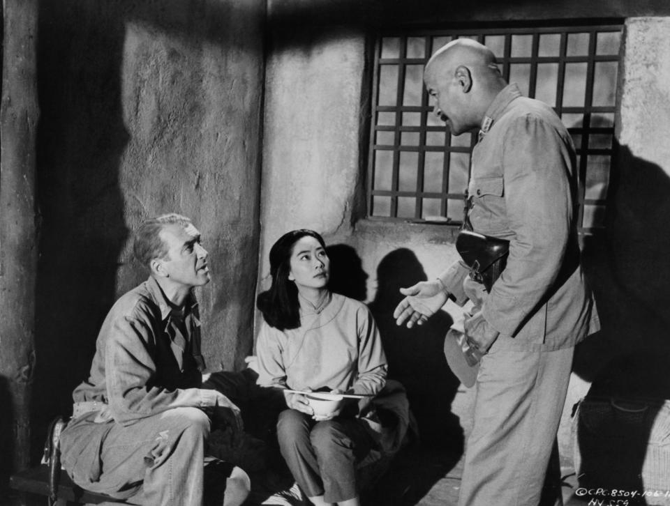 James Stewart and Lisa Lu are spoken to by unidentified man with gun in a scene from the film 'The Mountain Road', 1960