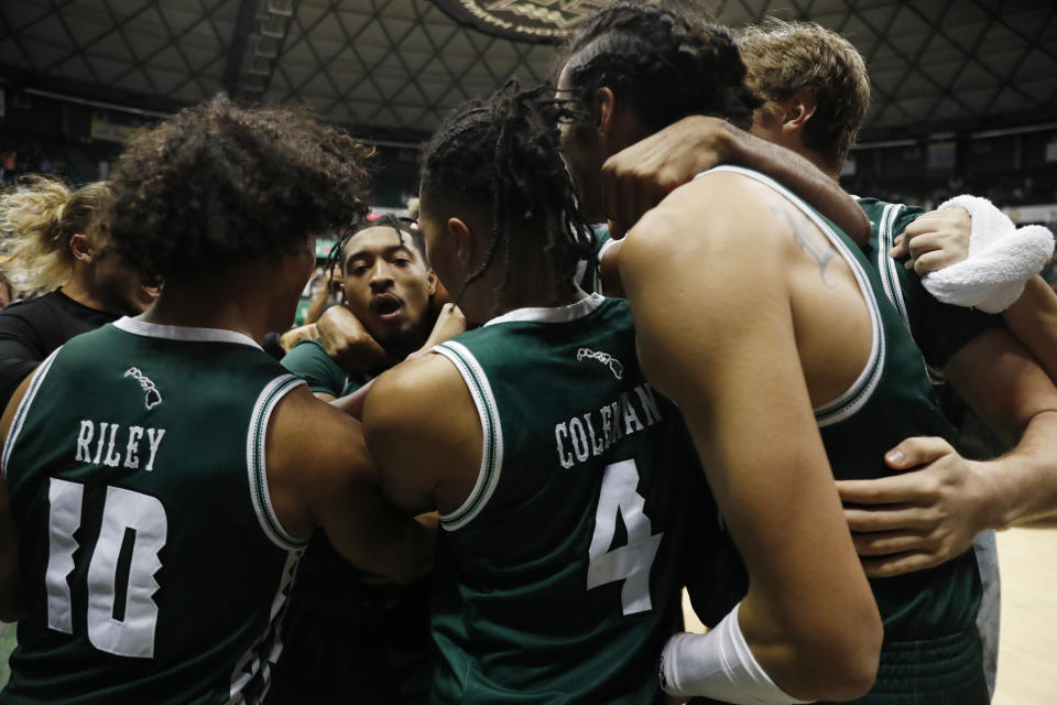 Hawaii guard JoVon McClanahan, center, reacts with teammates after making the winning shot over SMU to win the Diamond Head Classic NCAA college basketball game, Sunday, Dec. 25, 2022, in Honolulu. Hawaii defeated SMU 58-57. (AP Photo/Marco Garcia)