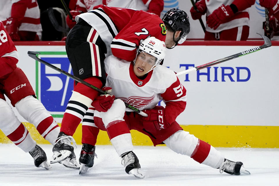 Detroit Red Wings right wing Dominik Shine, right, checks Chicago Blackhawks center Kirby Dach during the first period of an NHL preseason hockey game in Chicago, Wednesday, Sept. 29, 2021. (AP Photo/Nam Y. Huh)