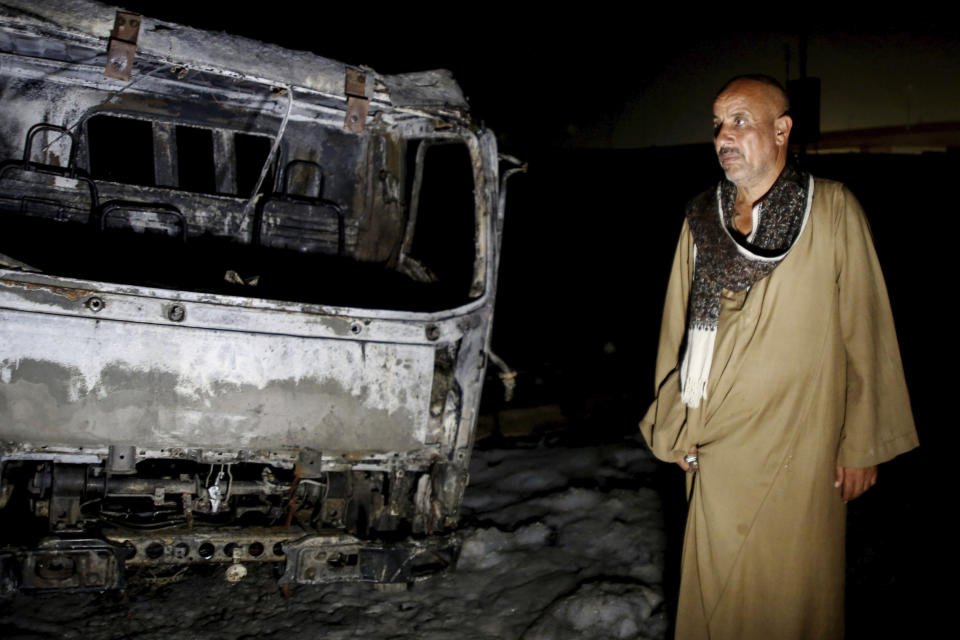 A man stands near burned vehicles following a fire that broke out in the Shuqair-Mostorod crude oil pipeline, on the Cairo-Ismailia road, in Egypt, Tuesday, July 14, 2020. A ruptured crude oil pipeline set off a monstrous blaze on a desert highway in Egypt on Tuesday, injuring at least 17 people, local authorities said. (AP Photo/Alaa Ahmed)