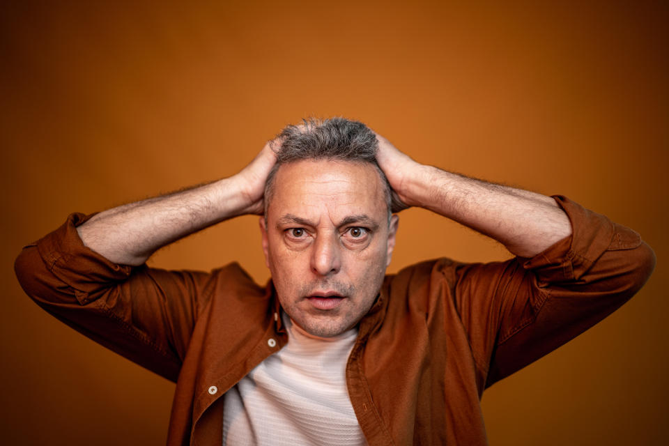 Portrait of a worried mature man on an orange background
