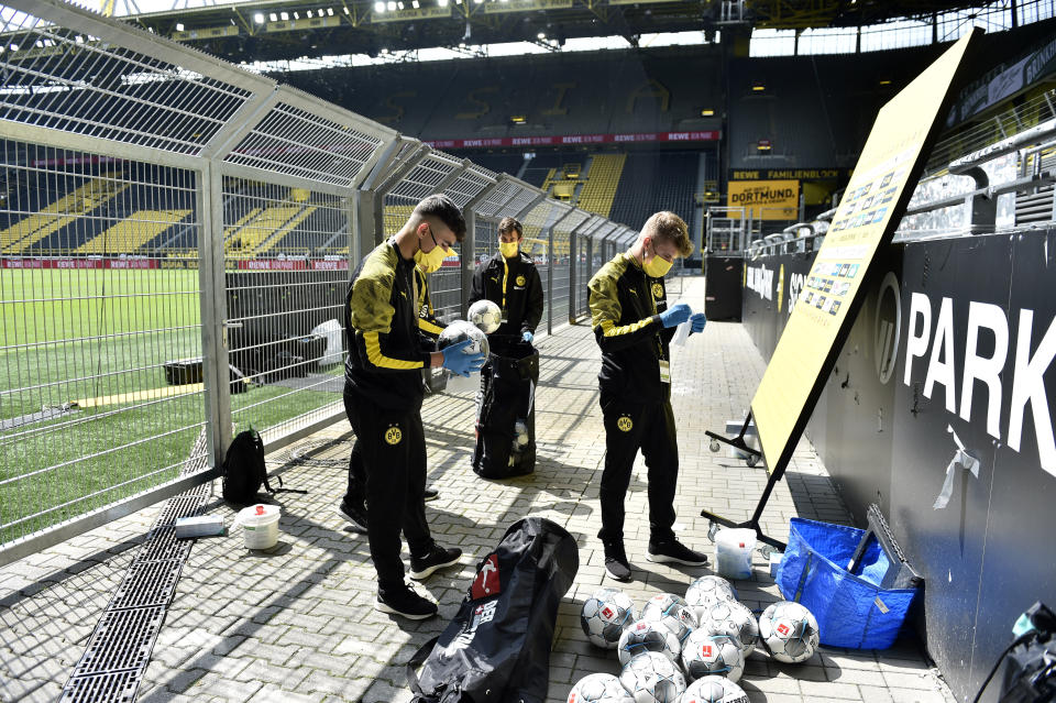 Ball boys disinfect the footballs before the German Bundesliga soccer match between Borussia Dortmund and Schalke 04 in Dortmund, Germany, Saturday, May 16, 2020. The German Bundesliga becomes the world's first major soccer league to resume after a two-month suspension because of the coronavirus pandemic. (AP Photo/Martin Meissner, Pool)