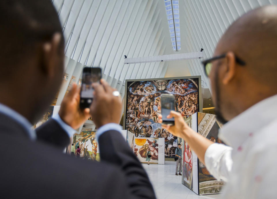 <p>Passersby take photos of the ‘Up Close: Michelangelo’s Sistine Chapel’ re-creation exhibit at the Oculus at Westfield World Trade Center in New York. The exhibit features 34 reproductions, including “The Creation of Adam” and “The Last Judgement.” (AP Photo/Michael Noble Jr.) </p>