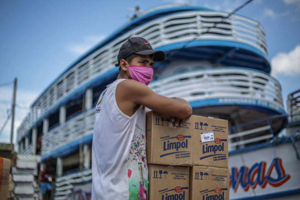 A man sits with cardboard boxes in front of a boat at Manaus port. Source: Getty Images