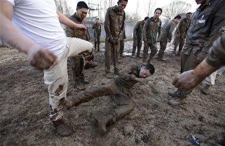 Instructors kick a trainee because he wants to give up during high intensity training at Tianjiao Special Guard/Security Consultant camp on the outskirts of Beijing December 1, 2013. REUTERS/Jason Lee