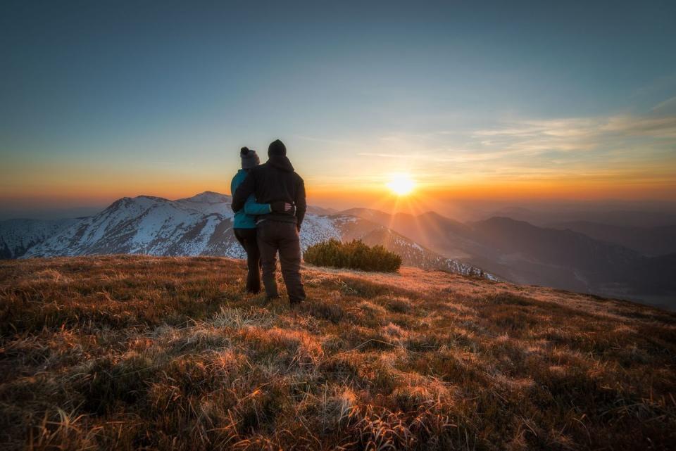 couple standing on hill at sunset