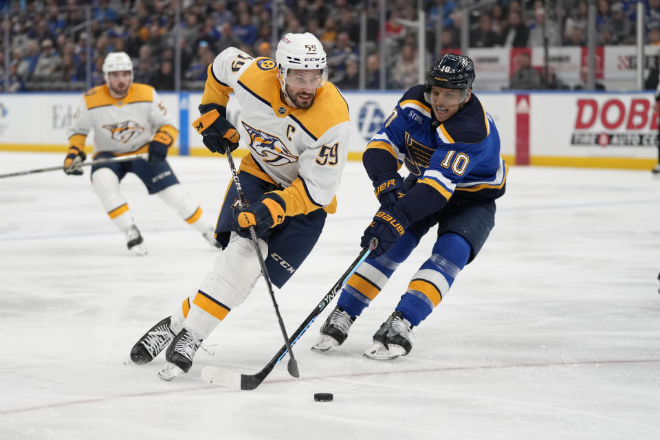 Nashville Predators' Roman Josi (59) brings the puck down the ice as St. Louis Blues' Brayden Schenn (10) defends during the first period of an NHL hockey game Monday, Dec. 12, 2022, in St. Louis. (AP Photo/Jeff Roberson)