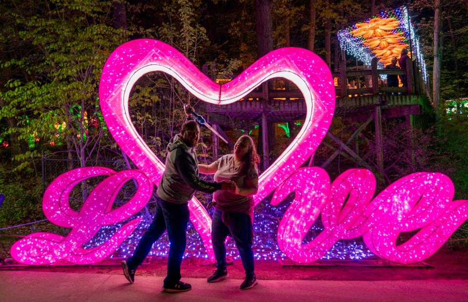 Mike Baldrica, 46, of Hudsonville, and his wife of 16 years, Tracy Baldrica, 42, strike an ironic pose in front of the illuminated "Love" lantern during their trek through the Grand Rapids Lantern Festival at the John Ball Zoo on Wednesday, May 8, 2024. "This is what I have to put up with," said Tracy, as they laugh together.