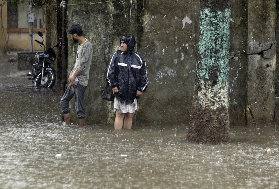 People wade through a waterlogged street following heavy rains in Mumbai, India, Tuesday, July 2, 2019. Heavy monsoon rains in western India caused at least three walls to collapse onto huts and city shanties, killing more than two dozen people and injuring dozens of others, officials said Tuesday, as forecasters warned of more rains. (AP Photo/Rajanish Kakade)