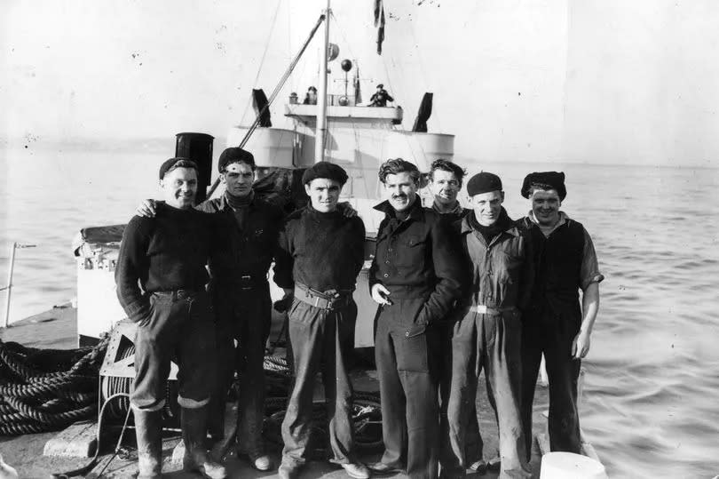 On board the blockade runner the Nonsuch with the blockade runner the Hopewell in the distance. Taken in March 1945. They were used to bring ball bearings from neutral Sweden to Britain to help in the war effort. Pictured are some of the crew aboard the Nonsuch. They have been together on all the blockade running trips