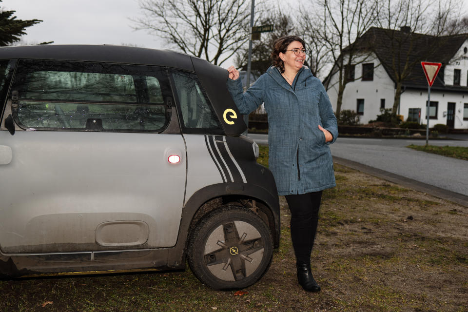 Astrid Nissen, resident of the village of Sprakebuell, stands next to an electric car in Sprakebuell, Germany, Thursday, March 14, 2024. Sprakebuell is something of a model village for the energy transition - with an above-average number of electric cars, a community wind farm and renewable heat from biogas. All houses in the village center have been connected to the local heating network and all old oil heating systems have been removed. (AP Photo/Frank Molter)