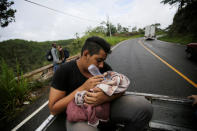 A Honduran migrant feeds a baby near of Agua Caliente while hoping to cross into Guatemala and join a caravan trying to reach the U.S., in Honduras October 17, 2018. REUTERS/Jorge Cabrera