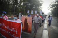 University teachers hold posters during a street march in Yangon, Myanmar, Friday, Feb. 26, 2021. Social media giant Facebook announced Thursday it was banning all accounts linked to Myanmar's military as well as ads from military-controlled companies in the wake of the army's seizure of power on Feb. 1. (AP Photo)