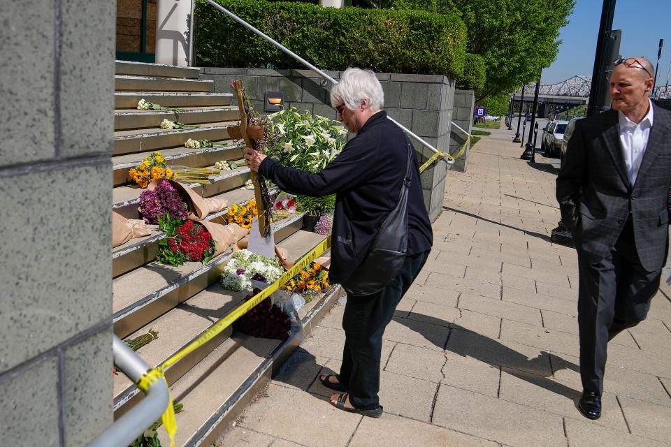 Jayne Hines places a cross outside of the Old National Bank Tuesday, April 11, 2023, a day after a mass shooting that left six dead, including the shooter, and another 8 injured. Hines lives across the street from the bank and wasn't home when the shooting happened. She returned several hours later home after spending the day at the zoo with her grandson.