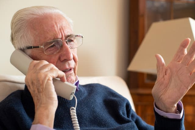 Senior Man Receiving Unwanted Telephone Call At Home