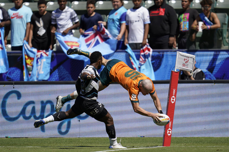 Australia's James Turner, right, leaps and goes over to score a try despite Fiji's Jerry Tuwai attempting to block during their Los Angeles rugby sevens series semifinal match at Dignity Health Sports Park in Carson, Calif., Sunday, 28, Aug. 27, 2022. (AP Photo/Marcio Jose Sanchez)