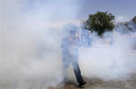 A Palestinian man runs away from tear gas fired by Israeli troops during a protest calling for the release of Palestinian prisoners held in Israeli jails, near an Israeli checkpoint in the West Bank town of Bethlehem April 4, 2014. REUTERS/Ammar Awad