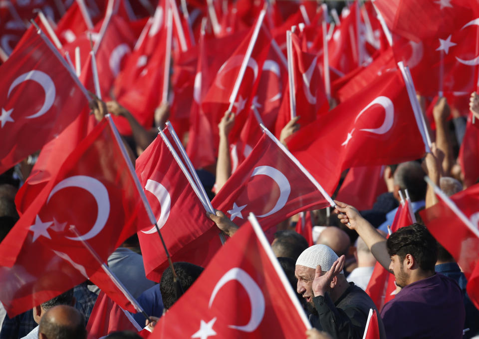 FILE - In this file photo dated Monday, July 15, 2019, people waving Turkish flags gather for a rally to honour the victims of the July 15, 2016 failed coup attempt, in Istanbul. Turkey’s combative president Recep Tayyip Erdogan enjoys widespread popular support within Turkey. (AP Photo/Lefteris Pitarakis, FILE)