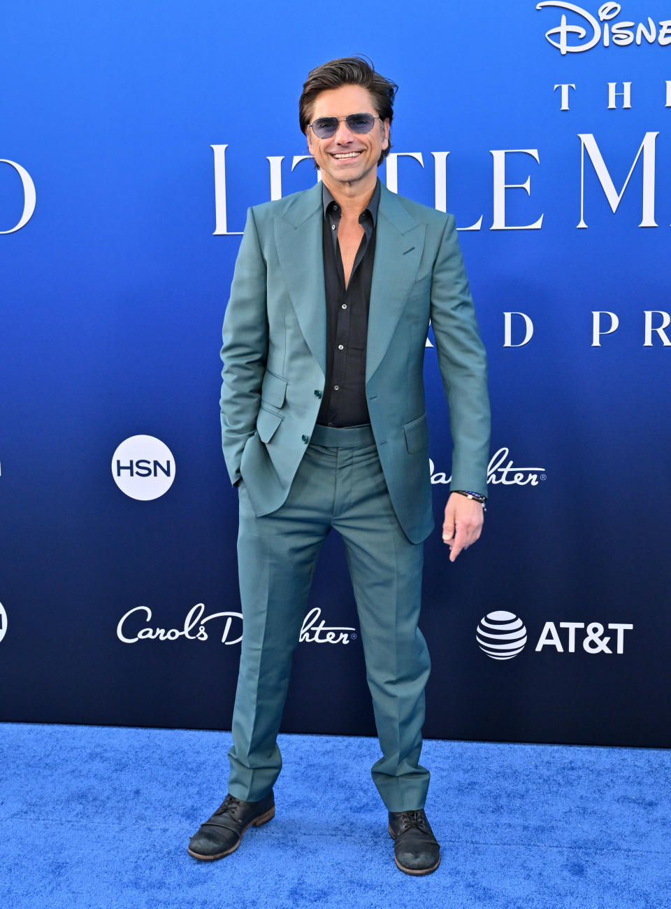 Close-up of John smiling in a suit, no tie, at a media event