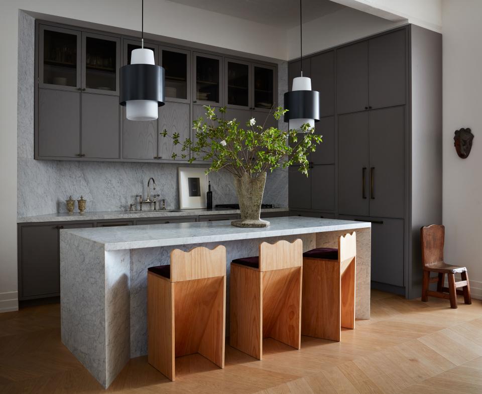 A 1950s French concrete vase sits on the marble island in the kitchen that Valle designed, along with the wood counter stools. The suspended lamps are Dutch from the 1960s; a carved wood child’s chair from the 1920s stands in the corner, and on the counter are a pair of alabaster vases and a framed work by Ed Ruscha.