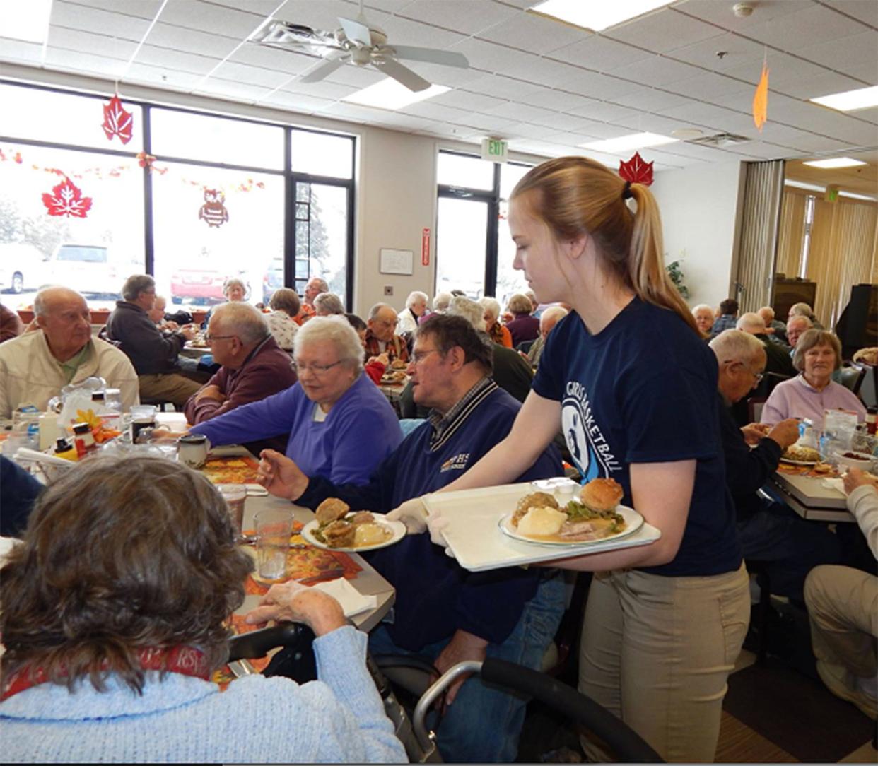 Pictured are seniors receiving and eating a meal at the Friendship Centers of Emmet County Council on Aging.