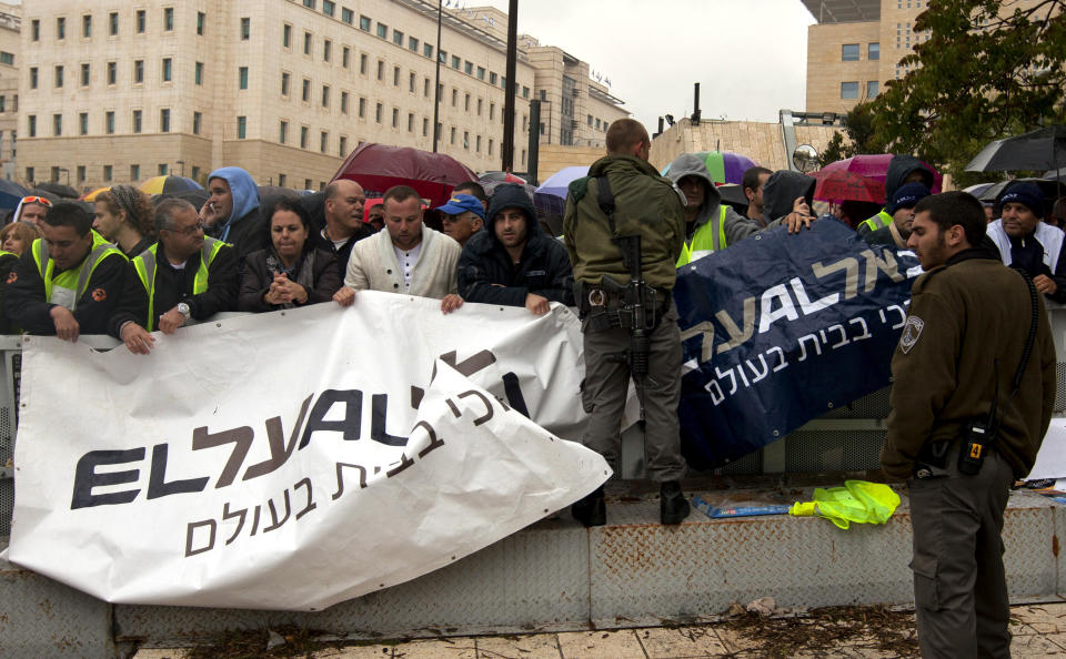 Israeli border police officers stand guard as Israeli airline workers hold signs during a demonstration in front of the prime minister's office in Jerusalem, Sunday, April 21, 2013. Israel's Cabinet on Sunday approved a deal to allow more EU flights, hours after the country's airlines went on strike out of concerns that the agreement would cost them jobs and possibly even ruin their companies.(AP Photo/Sebastian Scheiner)