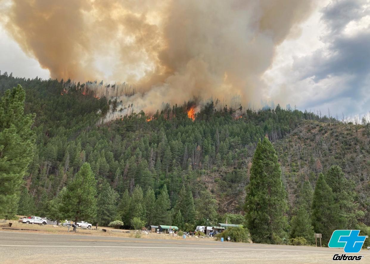 In this photo provided by Caltrans, smoke rises from the Head Fire in Klamath National Forest, Calif., on Tuesday Aug. 15, 2023. A wildfire pushed by gusty winds from a thunderstorm raced through national forest land near California's border with Oregon, prompting evacuations in the rural area. The blaze in Siskiyou County was one of at least 19 fires that erupted in the Klamath National Forest as thunderstorms rolling through the area brought lightning and downdrafts that drove the flames through timber and rural lands. (Roger Matthews/Catrans via AP)