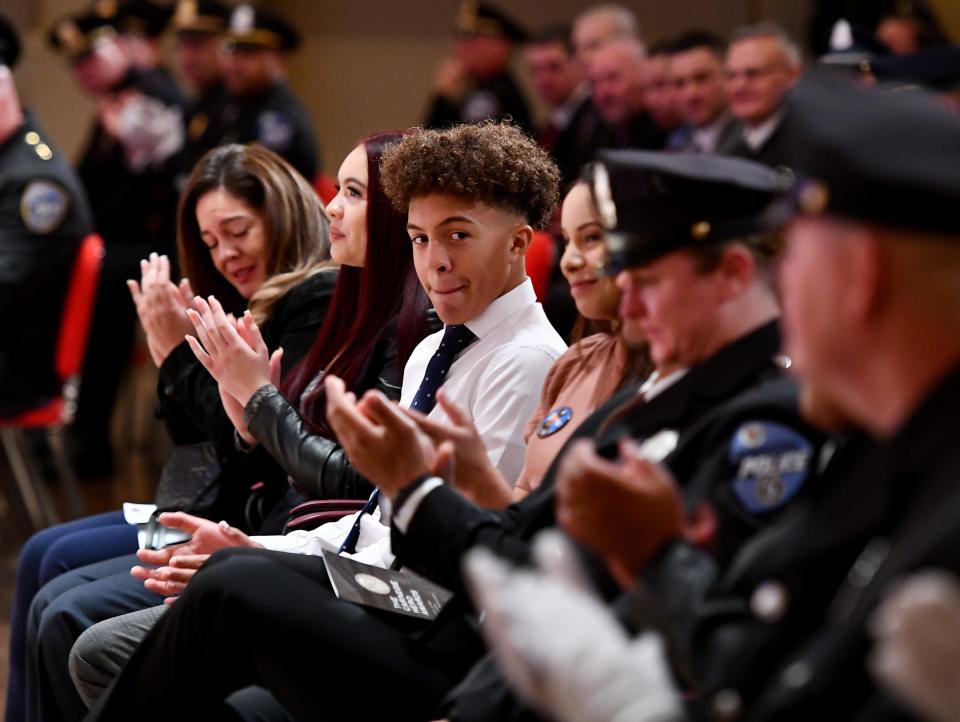 Jovan Familia, the son of fallen Worcester police Officer Enmanuel "Manny" Familia, applauds the Carnegie Medal recipients with his family during the ceremony at Mechanics Hall.